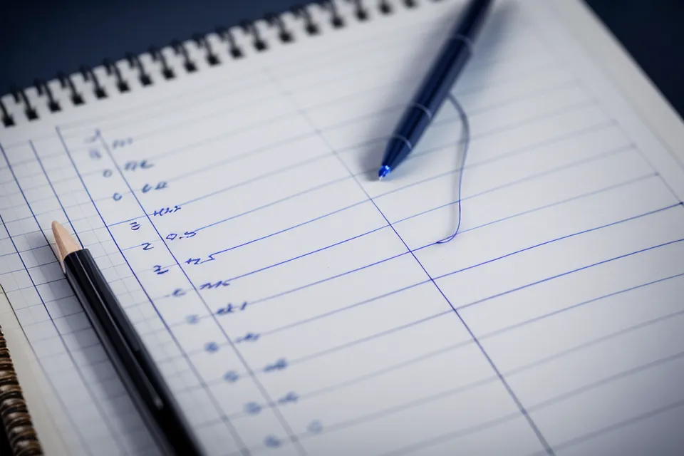 Detailaufnahme eines Notizbuchs mit handschriftlichen Notizen zu Steuerparagraphen und Kursmodulen.